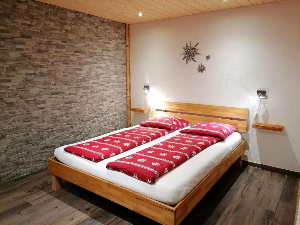 Una cama en una habitación con almohadas rojas. en "Studio Edelweiss" Spillstatthus, en Grindelwald