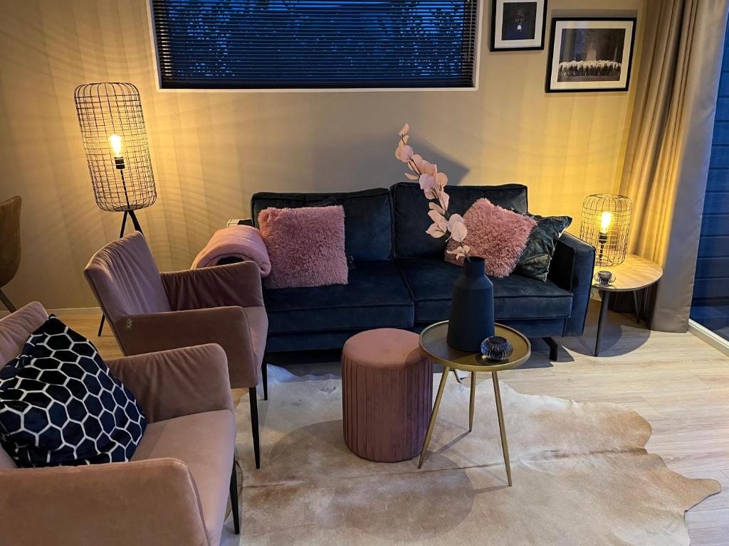 un soggiorno con divano blu e sedie di Luxus Chalet Waterfront a Lathum