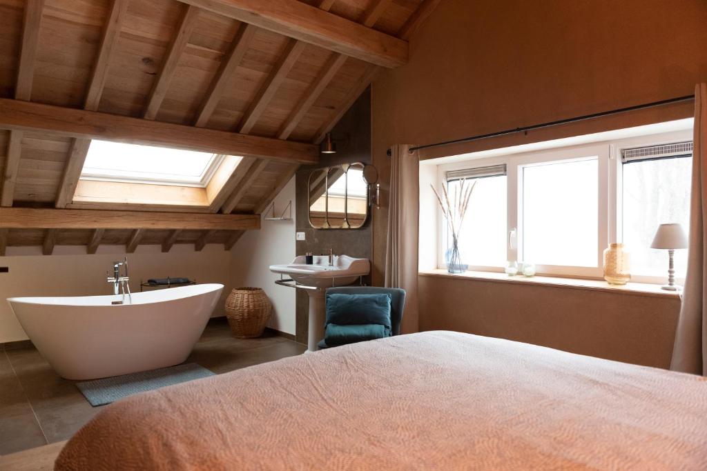 Schlafzimmer mit einem Bett, einer Badewanne und einem Waschbecken in der Unterkunft Le verger d' Adèle in Vielsalm