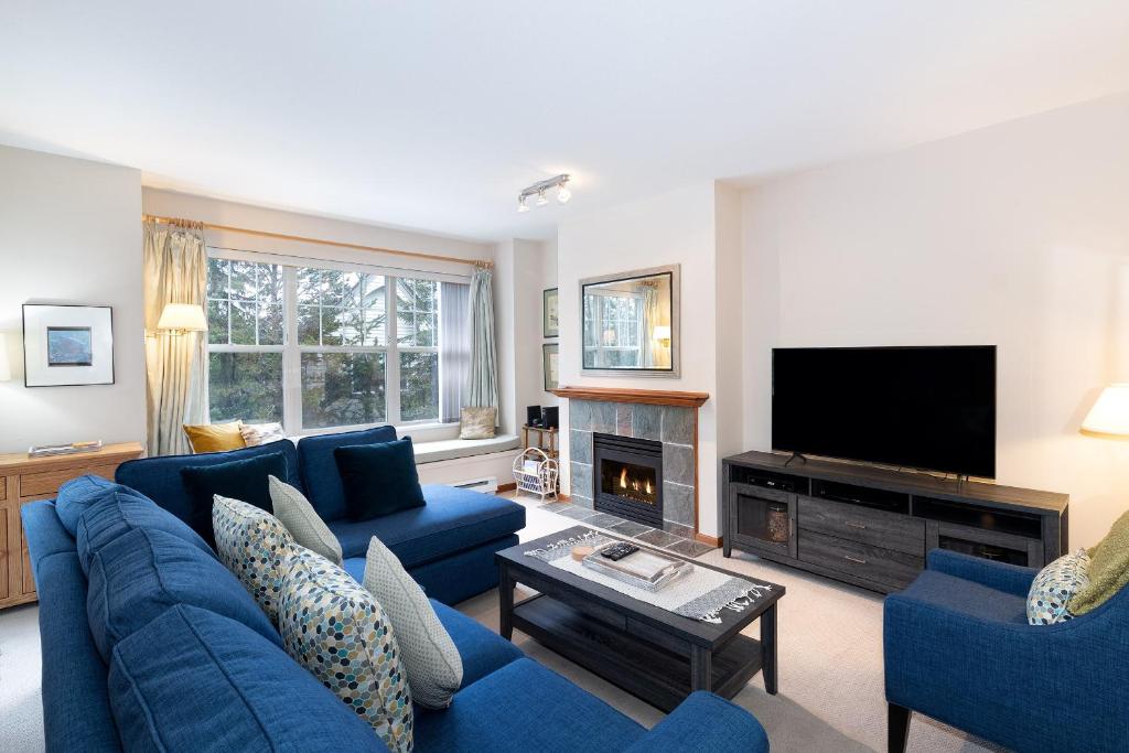 sala de estar con muebles azules y TV de pantalla plana en Deer Run by Whistler Premier, en Whistler