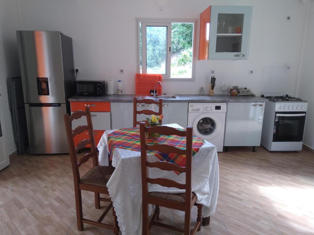 eine Küche mit einem Tisch, 2 Stühlen und einem Herd in der Unterkunft Le papillon bleu in Sainte-Anne