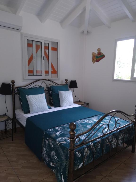 Schlafzimmer mit einem Bett mit blauer Bettwäsche und Kissen in der Unterkunft Le papillon bleu in Sainte-Anne