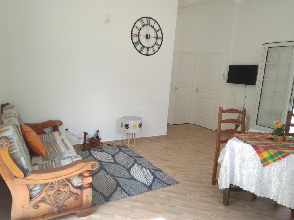 ein Wohnzimmer mit einem Stuhl und einer Uhr an der Wand in der Unterkunft Le papillon bleu in Sainte-Anne