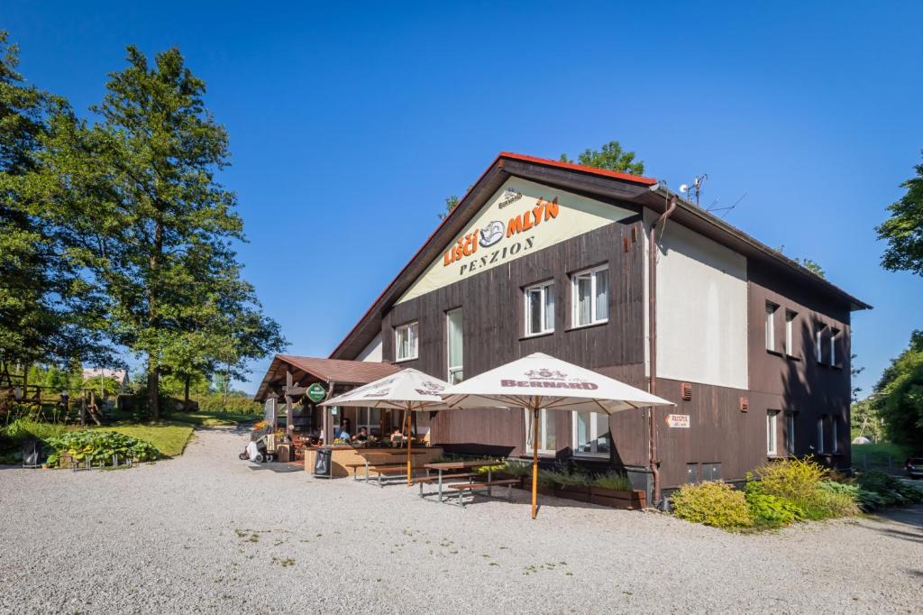 a building with tables and umbrellas in front of it at Liščí Mlýn in Frenštát pod Radhoštěm