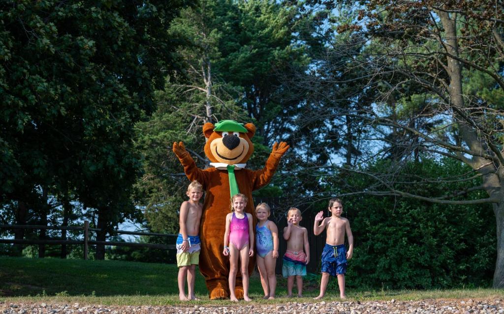 un grupo de niños parados frente a una mascota de oso en Yogi Bear's Jellystone Park Camp-Resort Wisconsin Dells, en Wisconsin Dells