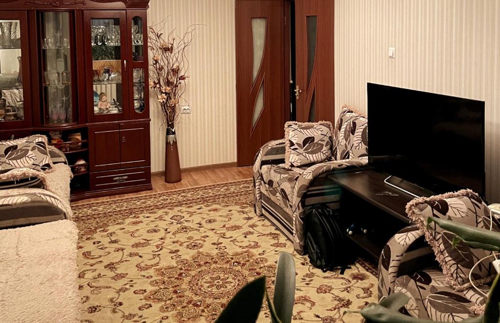 uma sala de estar com uma televisão, um sofá e uma cadeira em The12 отдельная комната em Bishkek