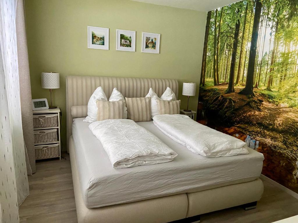 ein Bett mit weißer Bettwäsche und Kissen in einem Schlafzimmer in der Unterkunft Ferienwohnung Schloßberg Wohnung 2 in Eisenach
