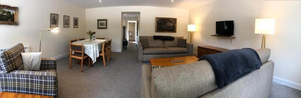 a living room with a couch and a table at Glenheurie Cottage in Polmood