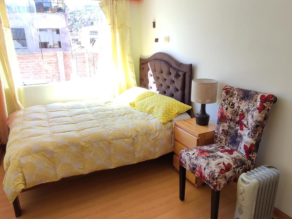 um quarto com uma cama, uma cadeira e uma janela em Cozy apartment in cusco em Cusco