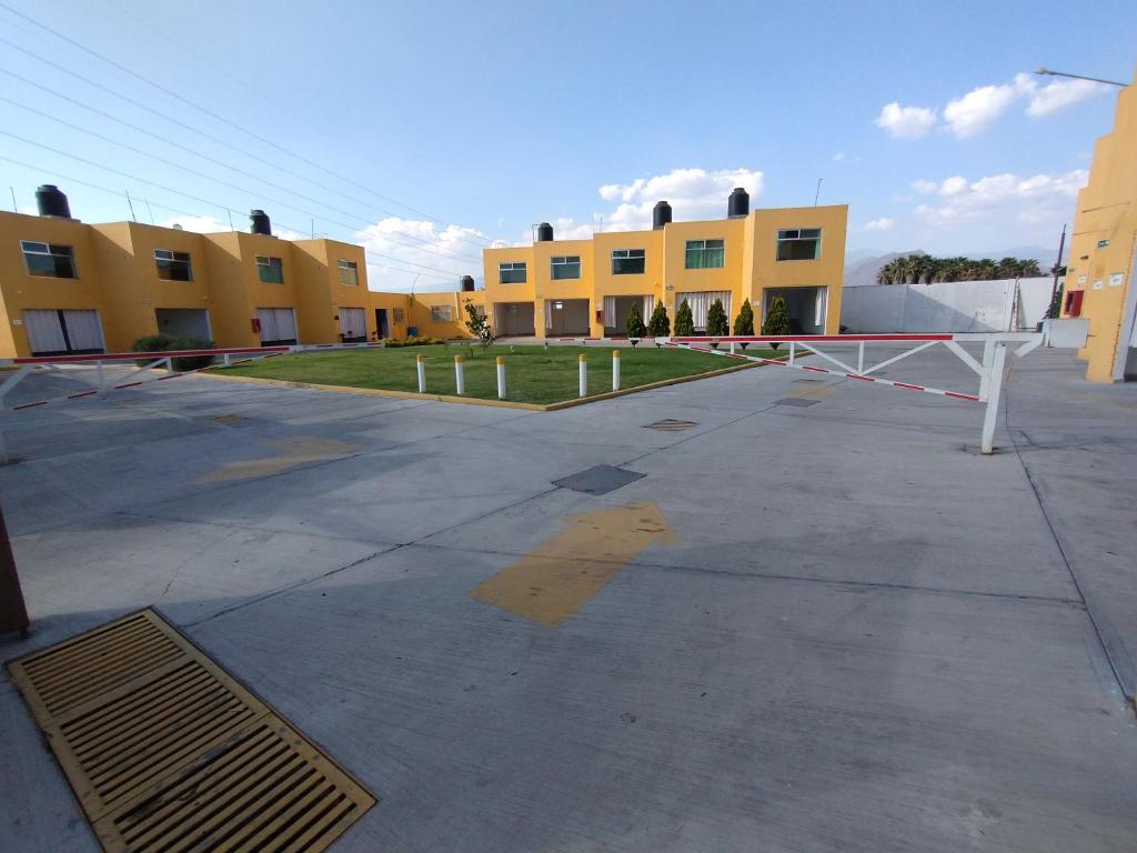 an empty parking lot in front of two yellow buildings at Hotel Villa Esmeralda in Cuautla Morelos