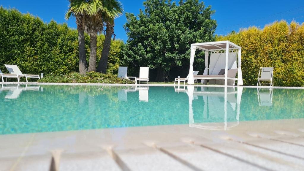 a pool with two chairs and a gazebo at I MESTRI Holiday Homes in Uggiano la Chiesa