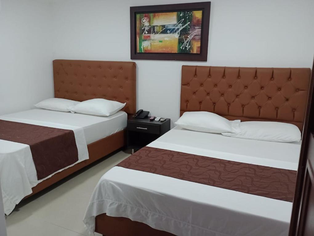1 dormitorio con 2 camas y una foto en la pared en Hotel Suite Imperial 72, en Barranquilla