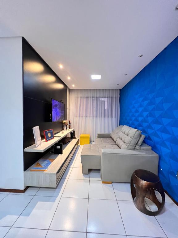 ein Wohnzimmer mit einem Sofa und einer blauen Wand in der Unterkunft Apartamento Ponta Verde-Pajuçara - Edf-Soho 2 Quartos - Castelo B Temporada in Maceió