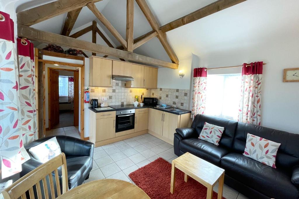 a living room with a couch and a kitchen at New Inn Lane Holiday Cottages in Evesham