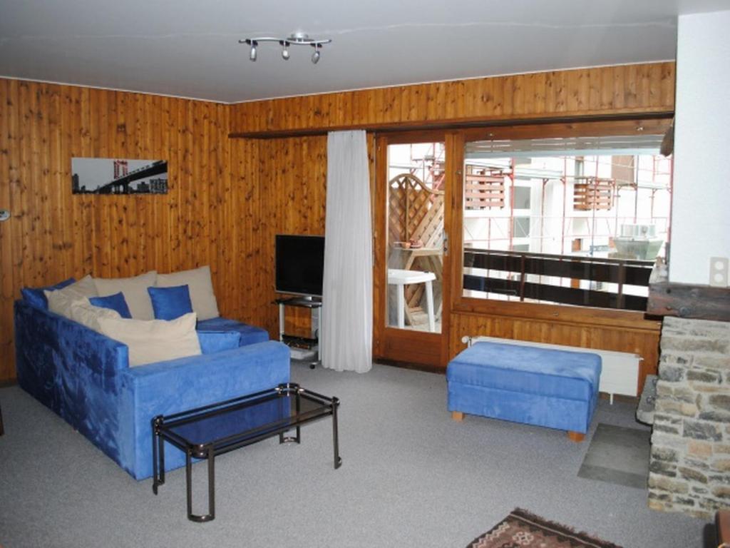 sala de estar con sofá azul y TV en Residence Alexia, en Crans-Montana