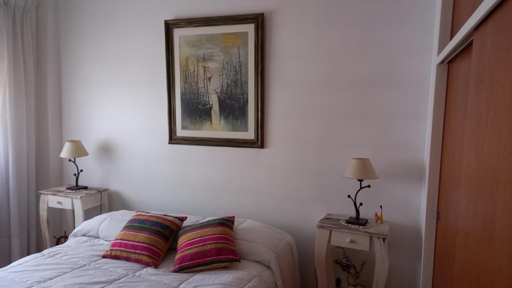 1 dormitorio con 1 cama con 2 lámparas y una foto en la pared en ALICIA V. en Villa Ballester