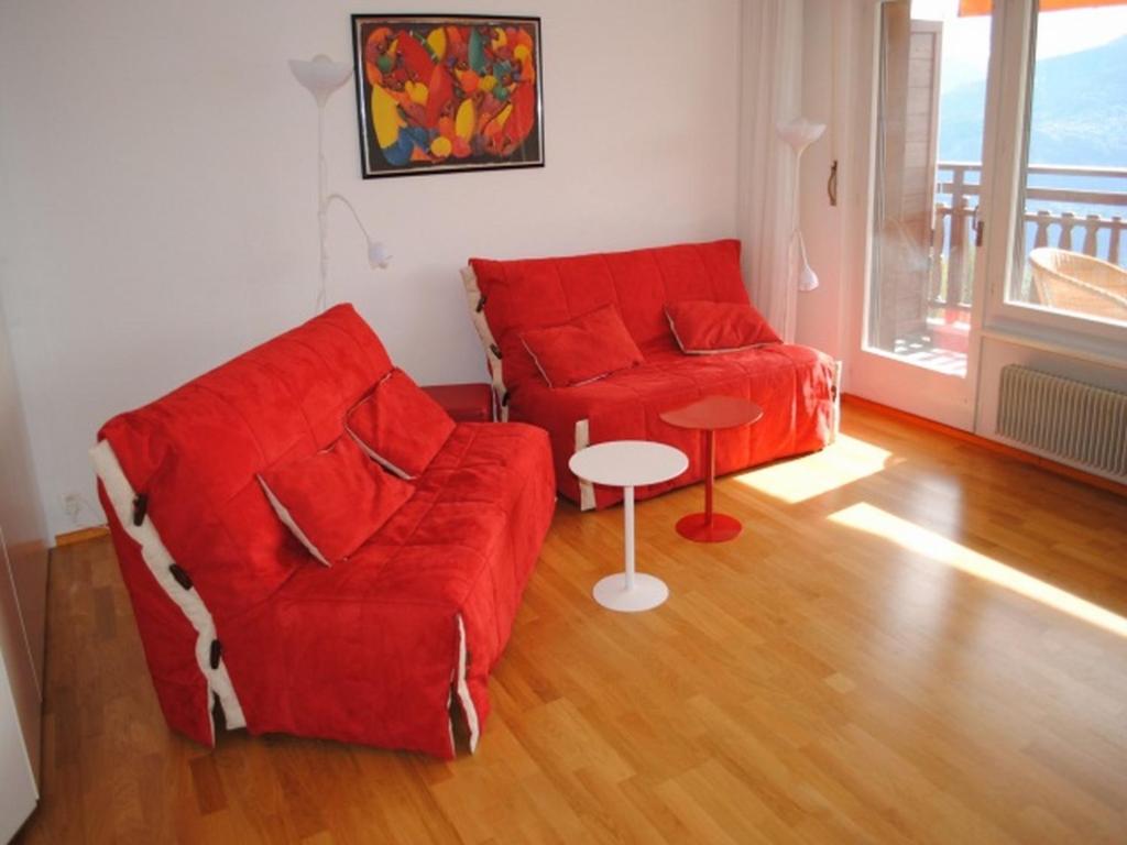 salon z czerwoną kanapą i stołem w obiekcie Residence Eden Roc w mieście Crans-Montana
