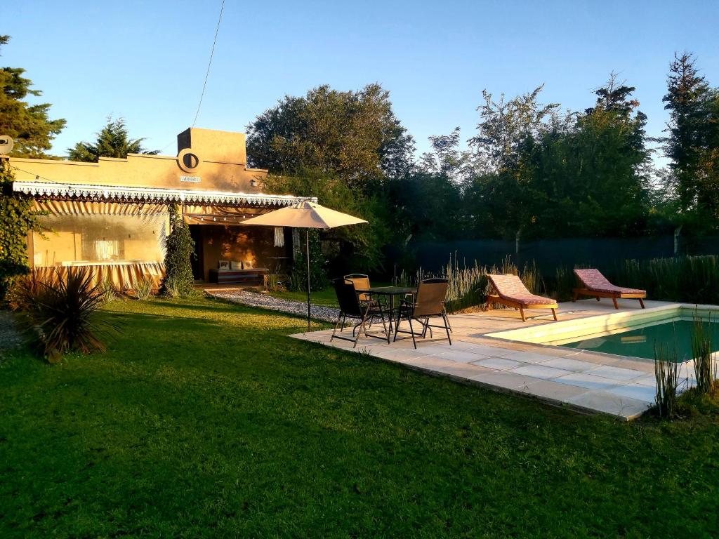 un patio trasero con mesa, sillas y piscina en La Ernestina en Villa Giardino