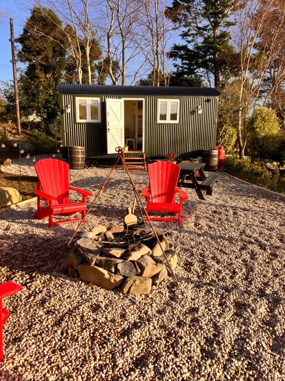 a tiny house with two red chairs and a fire pit at Ballydorn Stay in Killinchy