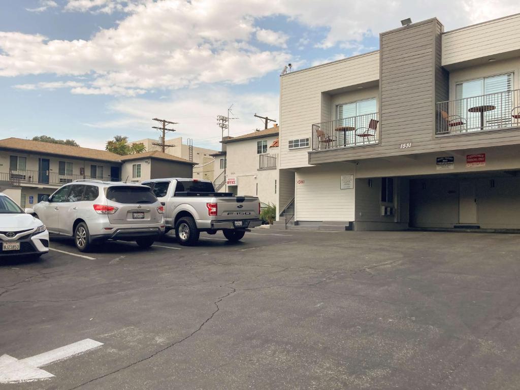 un estacionamiento con autos estacionados frente a un edificio en Motel 6 Glendale CA Pasadena Burbank Los Angeles, en Glendale