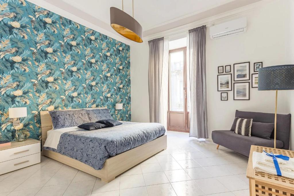 ein Schlafzimmer mit einem Bett und einer blauen Blumentapete in der Unterkunft Green Apartment Catania in Catania