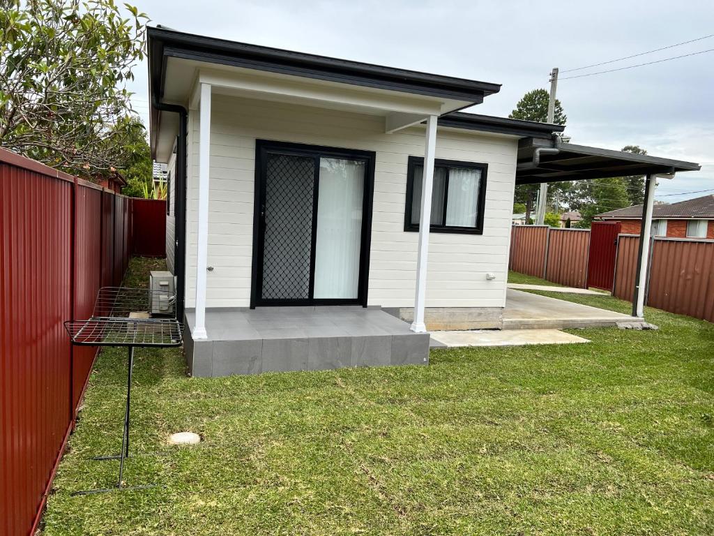 a small white house with a red fence at Fragrant Home-68A Brand New 2 rooms House with beautiful private garden and entrance,5G wifi in Doonside