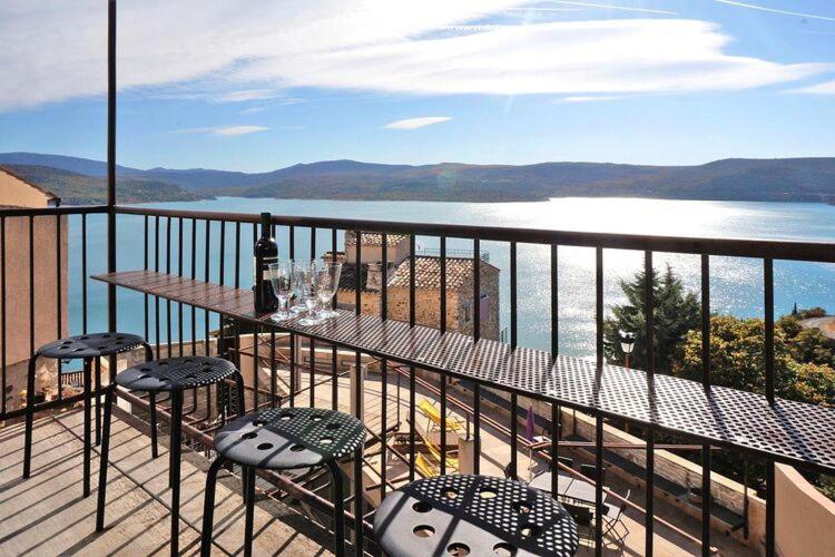 a balcony with a table and chairs and a view of the water at holiday home, Sainte-Croix-du-Verdon in Sainte-Croix-de-Verdon