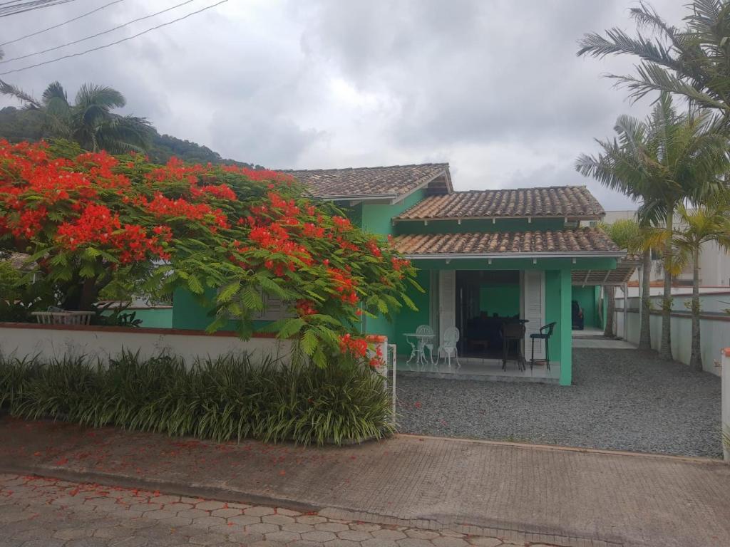 a green house with red flowers in front of it at Casa do Gaspar in São Francisco do Sul