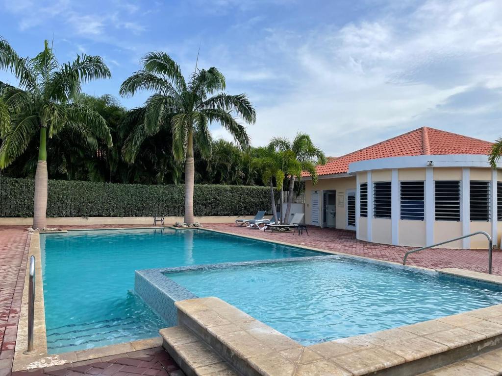 una piscina frente a una casa con palmeras en Dushi Townhouse Curaçao en Willemstad