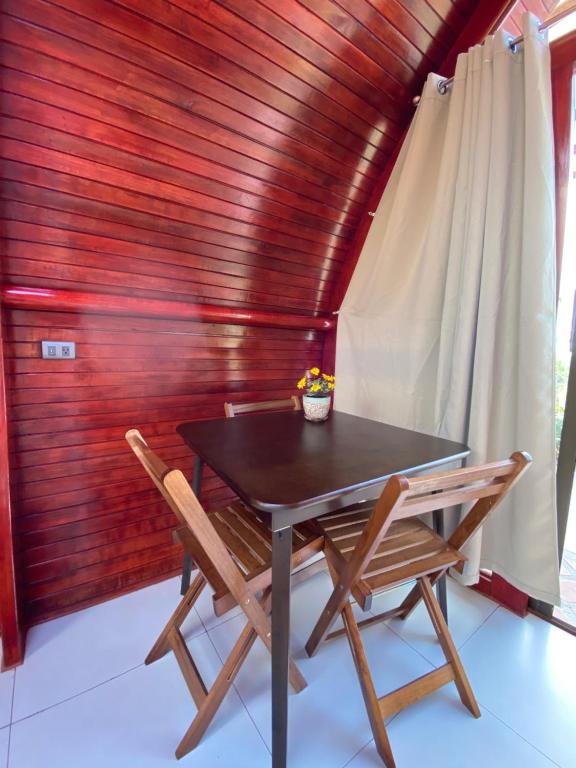 a table and chairs in a room with a wooden wall at Glamping Campo Alegre in Cartago