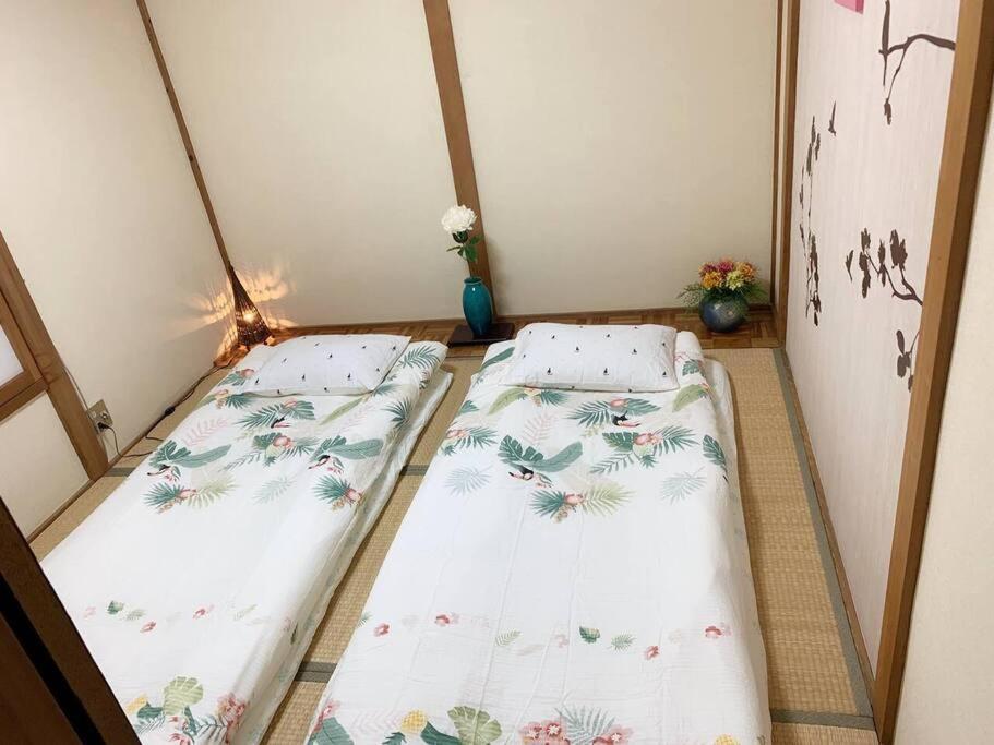 2 Betten in einem kleinen Zimmer mit Blumen in der Unterkunft 天下茶屋浪漫满屋 in Osaka