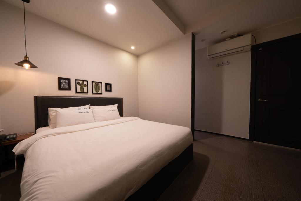 um quarto com uma cama grande e lençóis brancos em No25 Hotel Yeonsan em Busan
