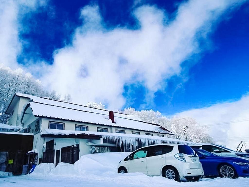 a white car parked in the snow in front of a house at Sachinoyu Hotel Shiga Kogen in Yamanouchi