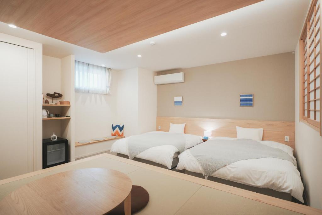 um quarto com 2 camas e uma mesa em NAGI Hiroshima Hotel and Lounge em Hiroshima