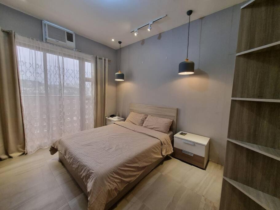 ein Schlafzimmer mit einem Bett und einem großen Fenster in der Unterkunft Cozy studio 5 min walk from Ayala, Cebu Business Park in Cebu City