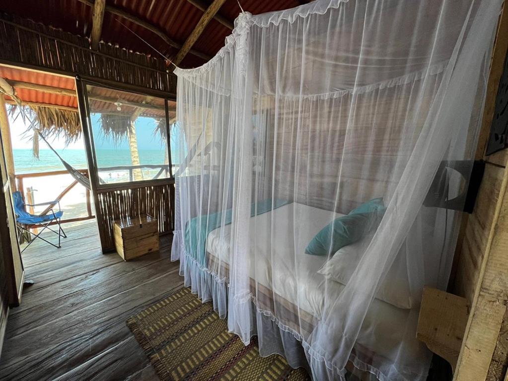 Schlafzimmer mit einem Himmelbett und Meerblick in der Unterkunft Palmarío Hostal in Guachaca