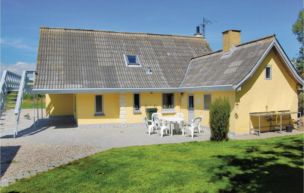 a yellow house with a table and chairs at Amazing Home In Rudkbing With 4 Bedrooms And Wifi in Spodsbjerg