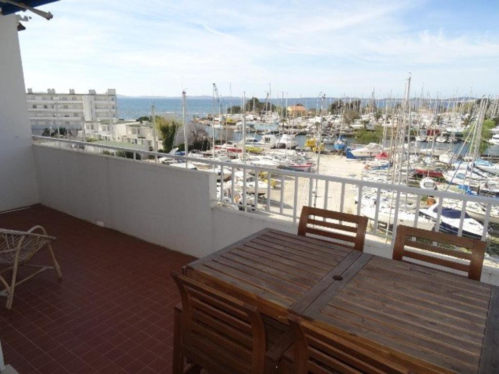 d'un balcon avec une table, des chaises et un port. dans l'établissement Appartement climatisé avec plage privée et parking à Hyères - FR-1-335-170, à Hyères