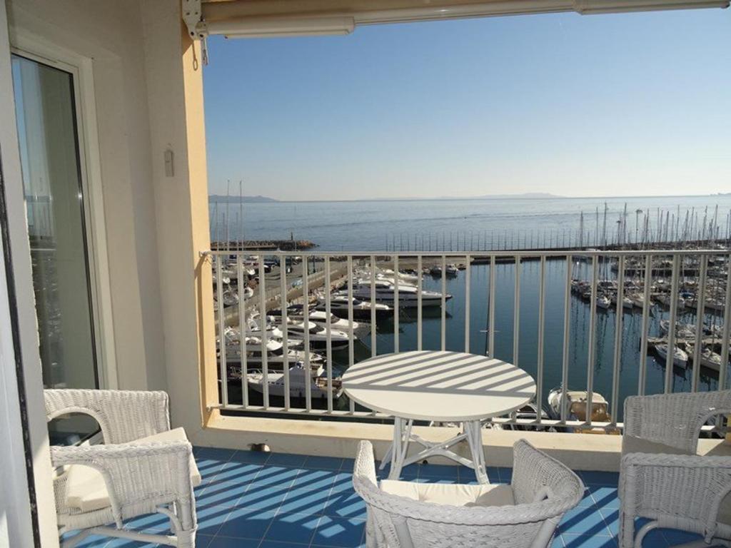 d'un balcon avec une table et des chaises et une vue sur le port de plaisance. dans l'établissement Appartement T2 + cabine climatisé, proche plage et commerces, Hyères Port - FR-1-335-172, à Hyères