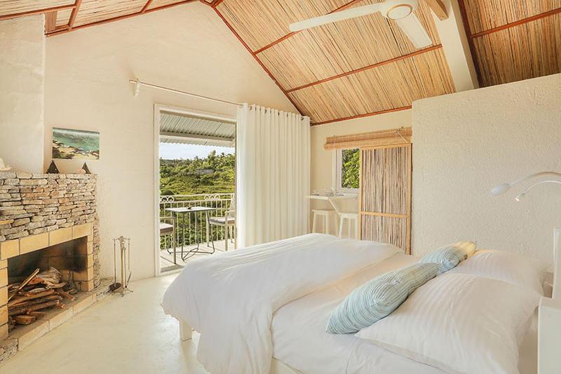 Dormitorio blanco con cama y chimenea en Fantaisie Lodges en Rodrigues Island