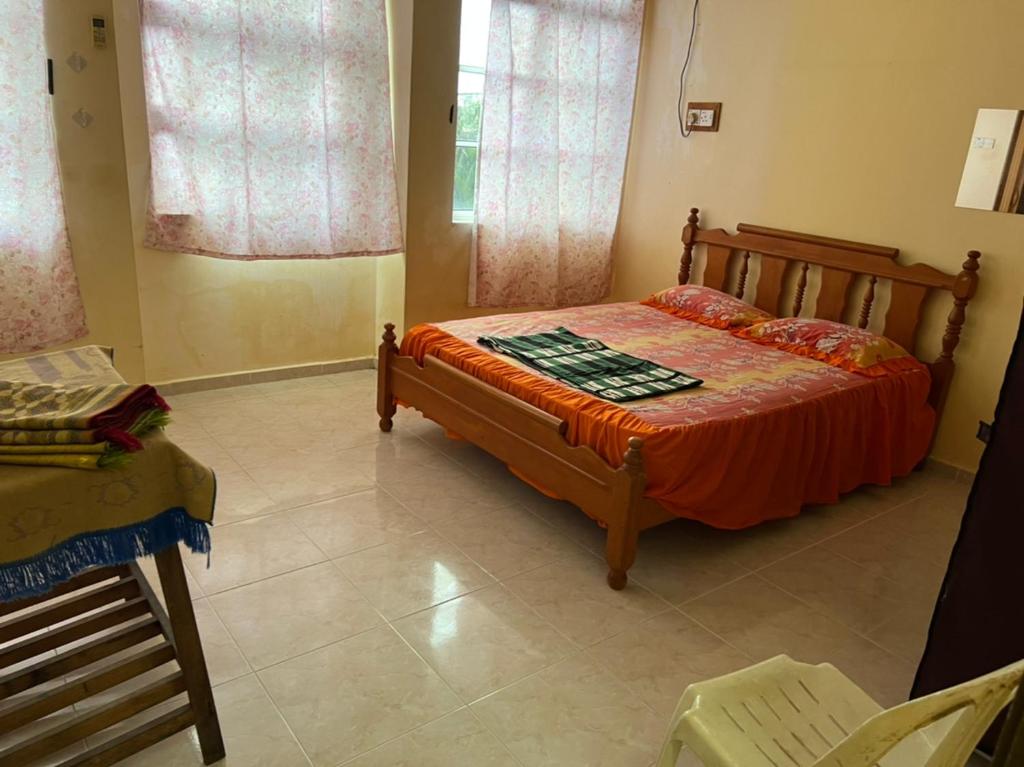 a bedroom with a bed and a chair and windows at Banglo Semi D Villa D Doa Maju in Kuala Terengganu