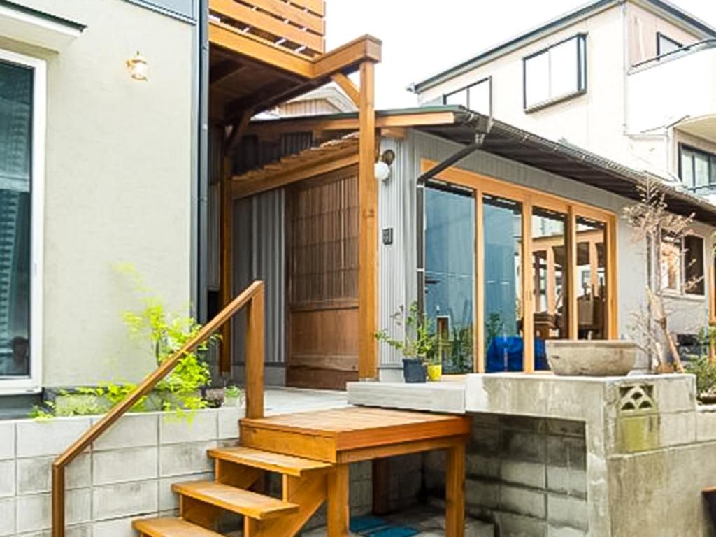 Casa con porche y banco de madera en Trawl Guesthouseトロールゲストハウス, en Koshigoe