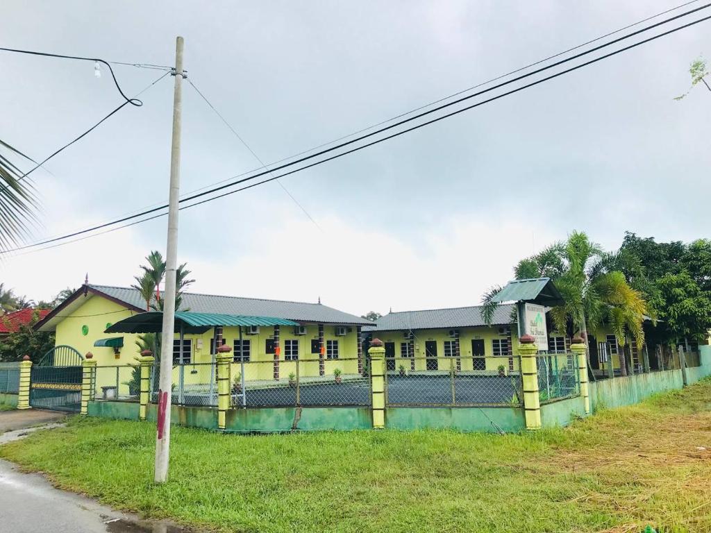 ein gelbes Gebäude mit einem Zaun davor in der Unterkunft Chalet Sri Damai in Kampong Pengkalan Maras