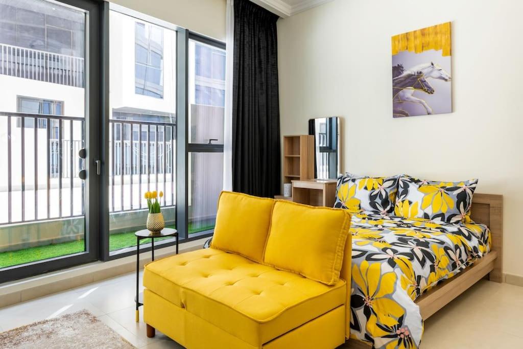 Brand New Studio Near Dubai Airport في دبي: غرفة نوم مع أريكة صفراء وكرسي اصفر