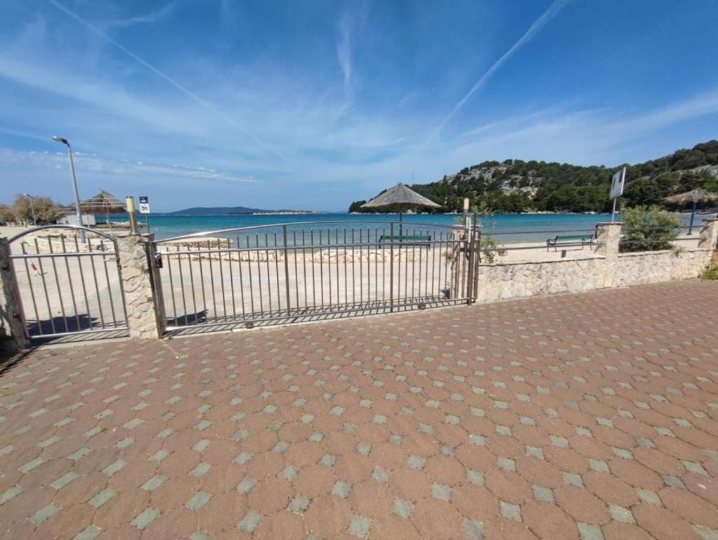 a fence on a beach with an umbrella and the ocean at Apartments Bionda - seafront in Zaboric