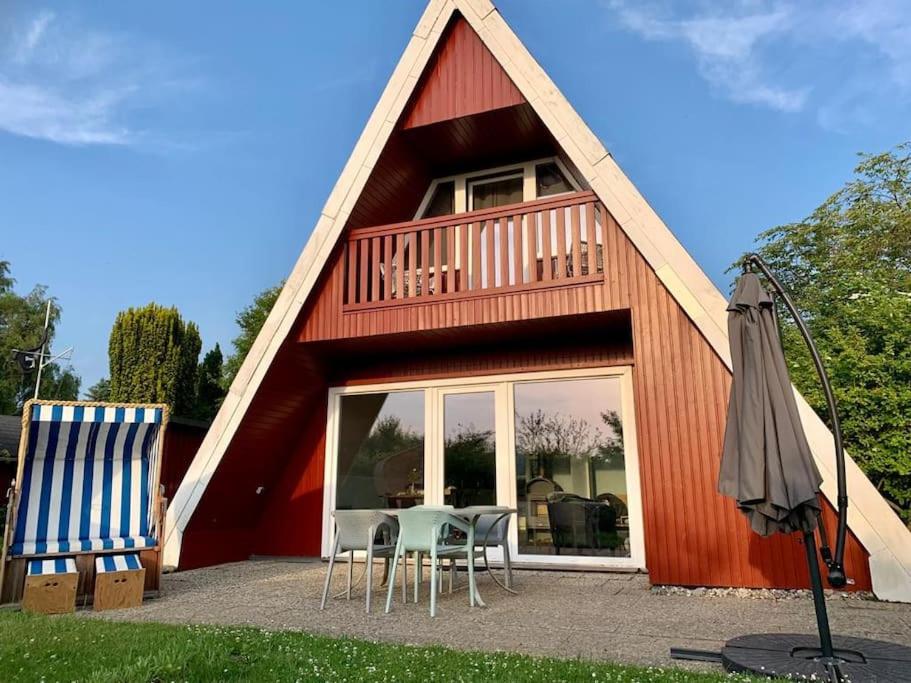 a red barn with two chairs and an umbrella at Ferienhaus Karlsson mit Blick auf die Ostsee in Hohenfelde