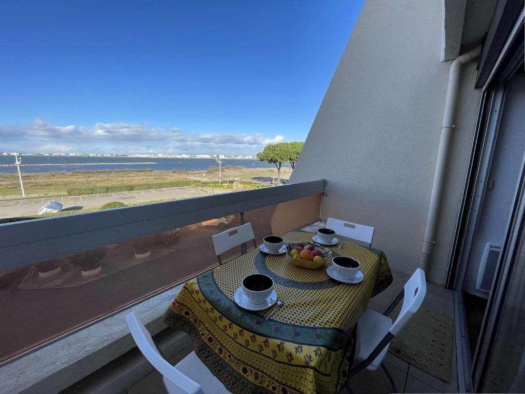 - une table avec 2 tasses et un bol de fruits sur le balcon dans l'établissement Studio cosy 4 pers, plage à pied, parking gratuit Port Camargue - FR-1-250-176, au Grau-du-Roi