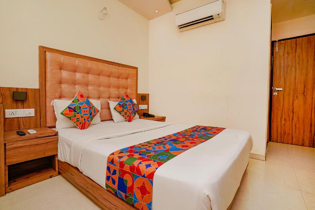 a bedroom with a large bed with a wooden headboard at FabExpress Emerald Inn in Mumbai