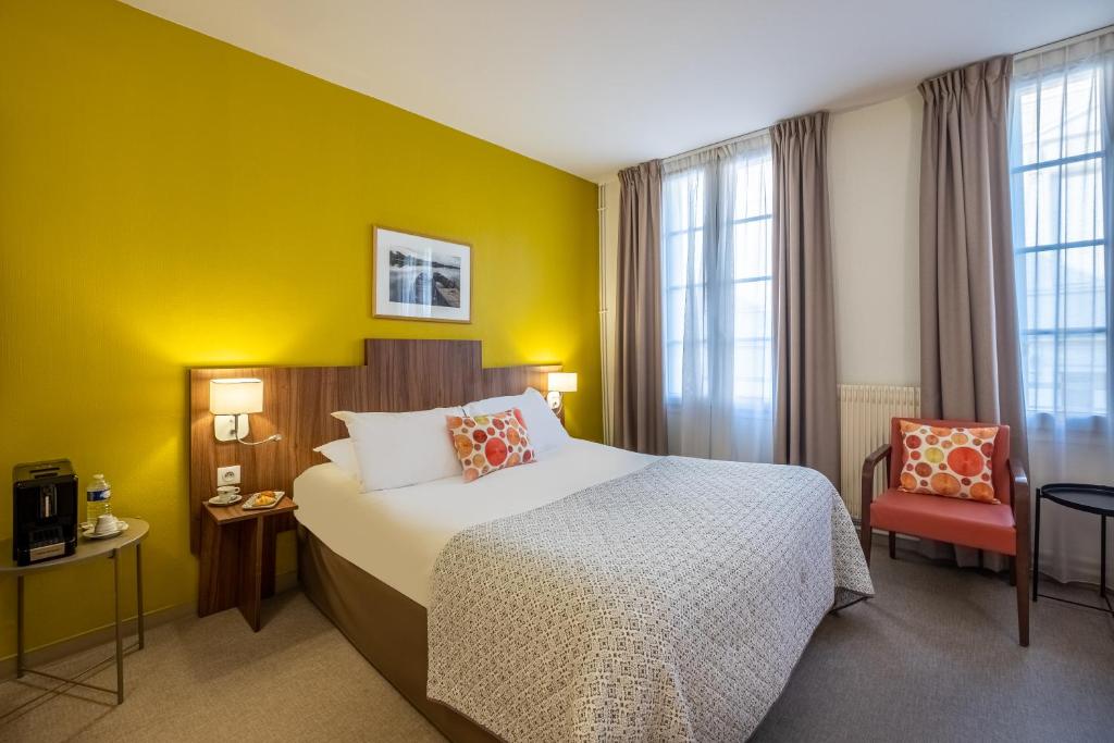 a hotel room with a bed and a yellow wall at Logis Hôtel Restaurant Chaptal, Amboise in Amboise