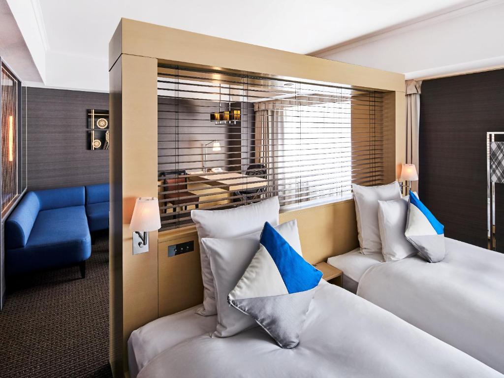 a hotel room with two beds and a blue couch at ANA Crowne Plaza Kanazawa by IHG in Kanazawa